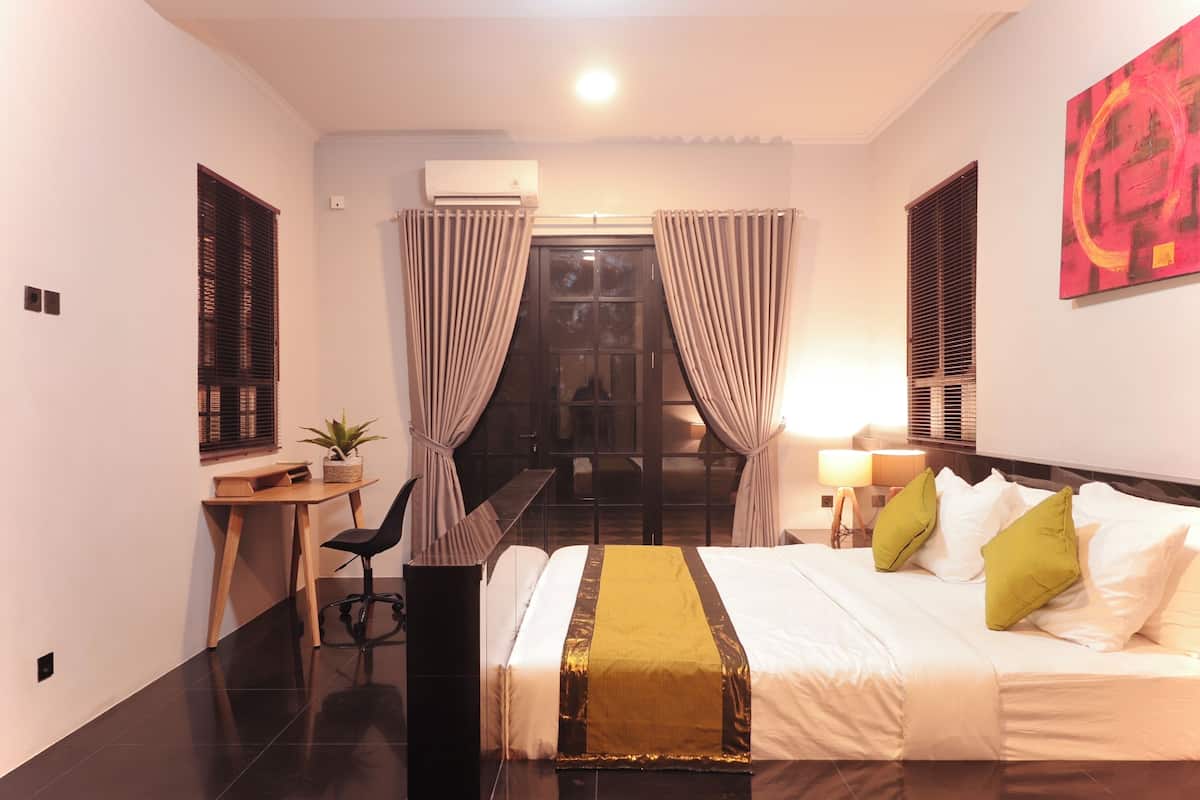 Ein Hotelzimmer mit Bett, Schreibtisch, Stuhl und einem Fenster mit Vorhängen.