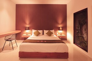 A modern bedroom with a large bed, two bedside tables with lamps, a wooden desk, and a large window with blinds.