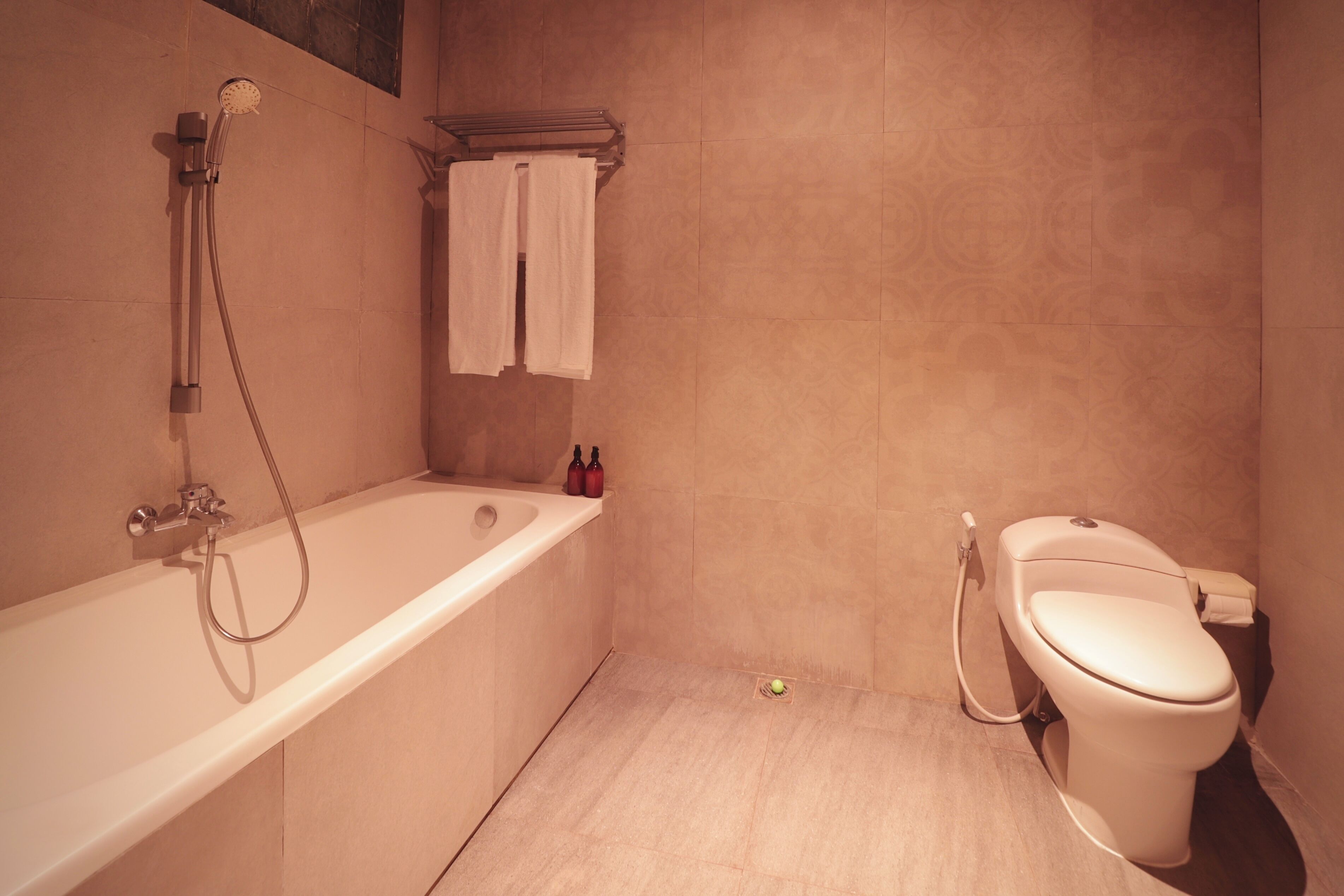 A bathroom with a bathtub, toilet, and a towel rack.