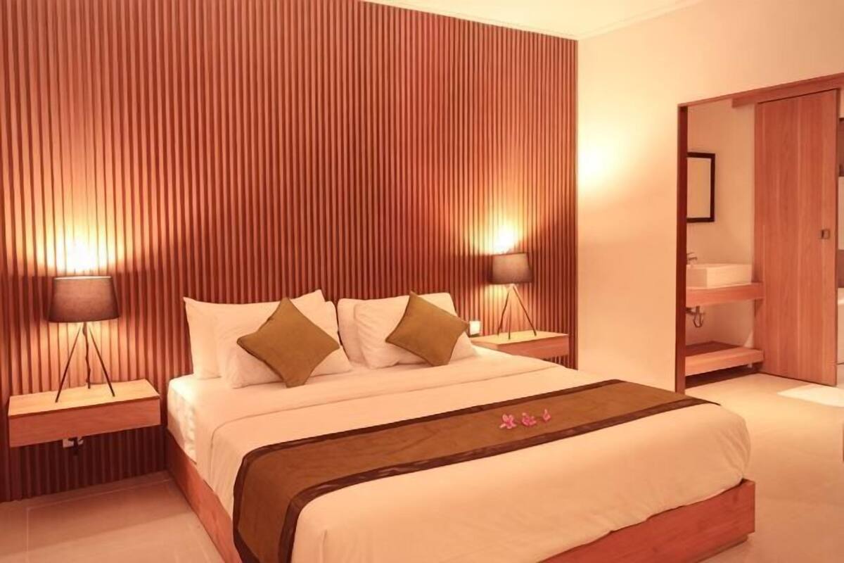 Ein Hotelzimmer mit einem Bett, Nachttischen, einem Spiegel und einem Kleiderschrank.