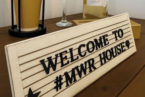A wooden sign with the text "WELCOME TO #MWR HOUSE".