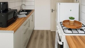 A kitchen with a microwave, sink, stove, and cabinets. - 1 Bed Flat - Sleeps 3 - Parking - Pet friendly (South Shields)