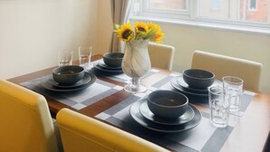 A dining table set with black bowls, glasses, and a vase with sunflowers. - 1 Bed Flat - Sleeps 3 - Parking - Pet friendly (South Shields)