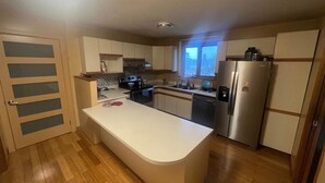 A modern kitchen with a central island, stainless steel appliances, and a window providing natural light. - Morning BNB (Gurugram)
