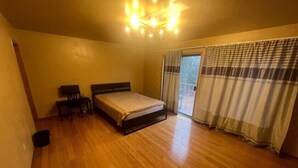 A bedroom with a bed, a chair, a desk, and a window with curtains. - Morning BNB (Gurugram)