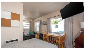 Un dormitorio con cama, escritorio y silla. Hay una ventana con cortinas y vistas al exterior.