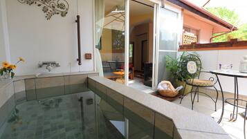 A glass-enclosed hot tub area with a view of the patio and a dining table.