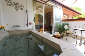 A glass-enclosed hot tub area with a view of the patio and a dining table. - chiisana hoteru seravi (Nagatoro)