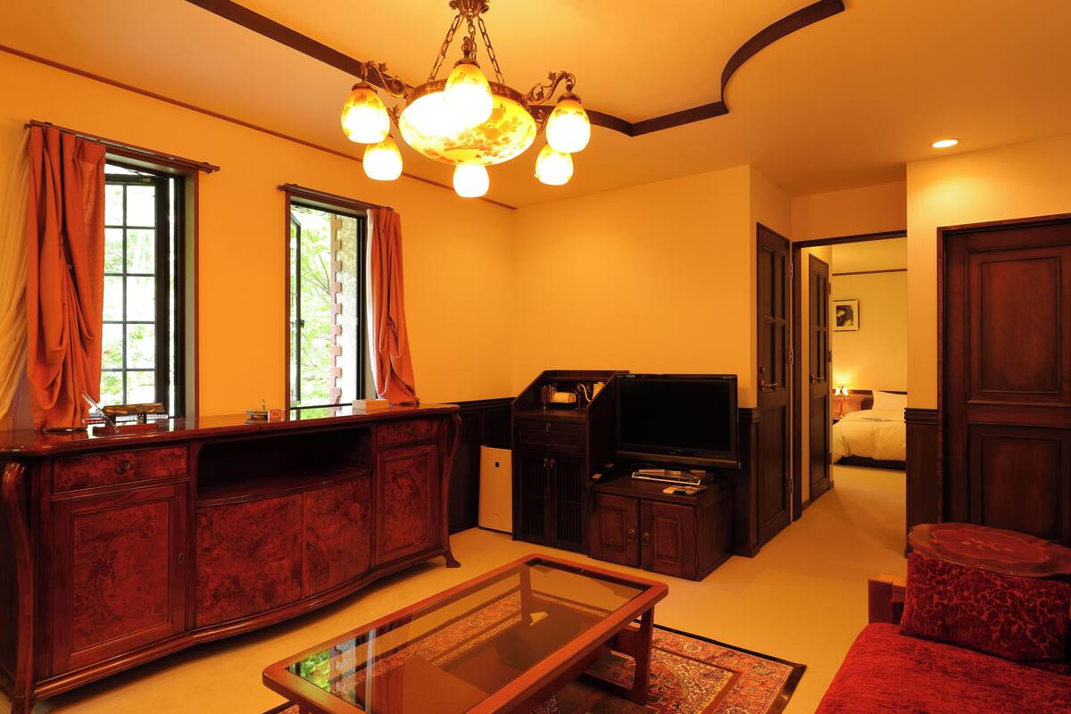 A living room with a wooden cabinet, a glass coffee table, a television, and a red sofa.