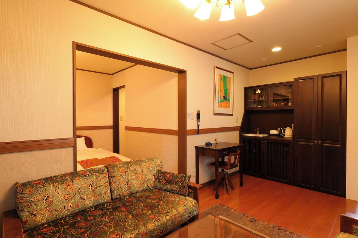 A room with a sofa, a bed, a desk, and a cabinet.