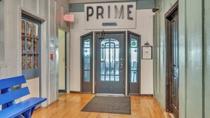 A hallway with a wooden floor, a blue bench, and a door labeled "PRIME" with a sign above it. - Penthouse Suite, gorgeous West Lake Okoboji views, 1 BDRM above shopping center (Arnolds Park)