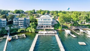 A waterfront hotel with a central building labeled "CENTRAL EMPORIUM," featuring a dock and boats. - Penthouse Suite, gorgeous West Lake Okoboji views, 1 BDRM above shopping center (Arnolds Park)