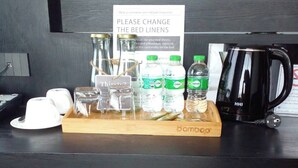 A hotel room's minibar area with a sign requesting guests to change bed linens, a tray with toiletries, and a coffee maker. - BB hotel Savannakhet Laos (Savannakhet)