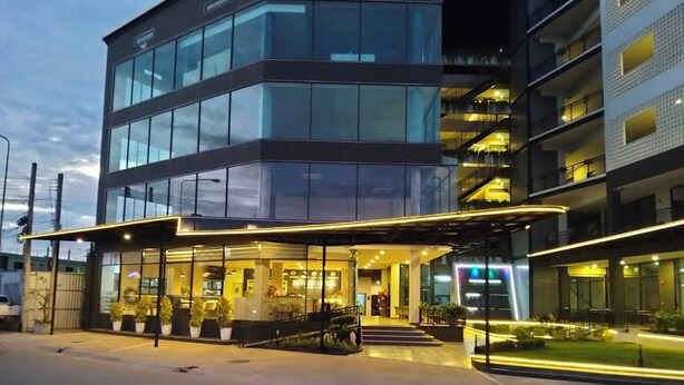 A modern hotel with a glass facade, outdoor seating area, and a well-lit entrance. - BB hotel Savannakhet Laos (Savannakhet)