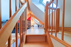 Una escalera de madera conduce a un dormitorio en un altillo con tragaluz.