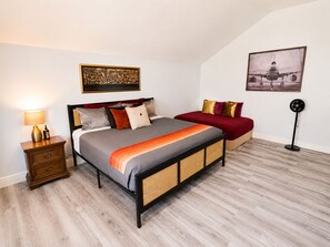 Un dormitorio con una cama, mesita de noche, lámpara y dos cuadros en la pared.