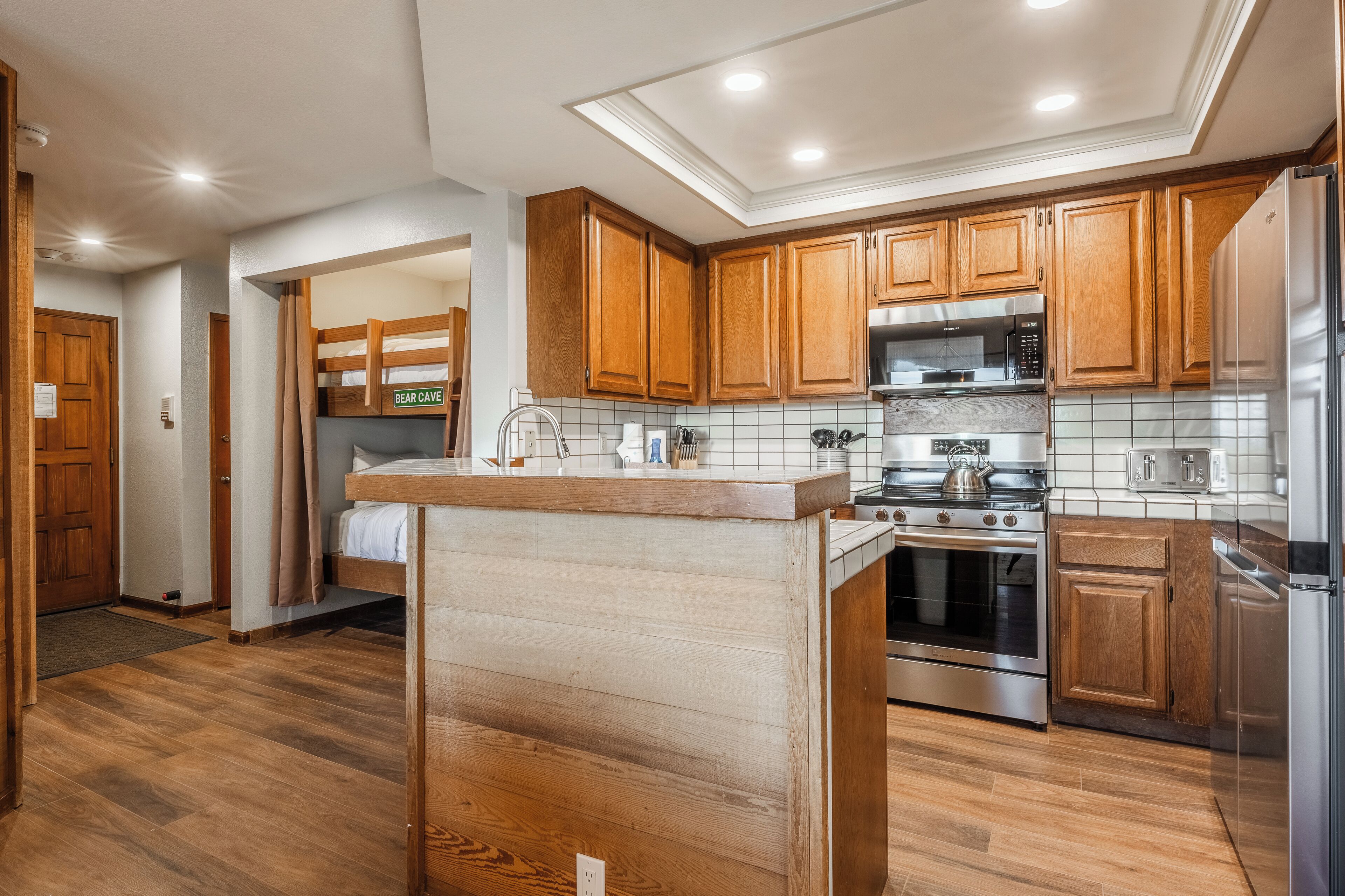 Una cocina moderna con armarios de madera, un refrigerador de acero inoxidable y un horno empotrado.