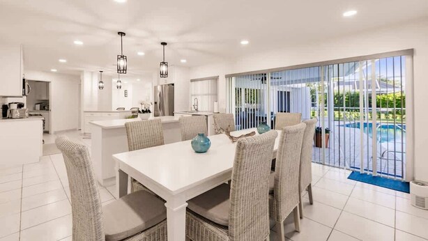 Une cuisine moderne avec des meubles blancs, un îlot central et des luminaires suspendus.