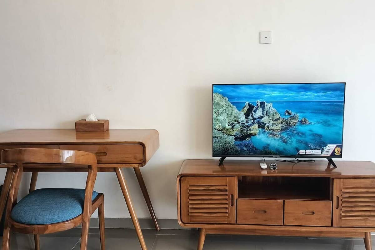 Un bureau en bois, avec une chaise et un téléviseur posé sur un meuble en bois.