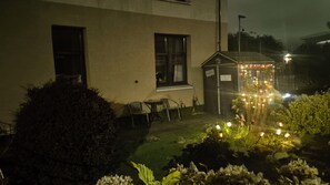 Un bâtiment doté d’un petit porche, d’une enseigne et d’un jardin illuminé.