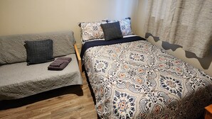 A bedroom with a bed, a sofa, and a window with curtains.