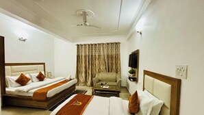 A hotel room with two beds, a sofa, a TV, and a ceiling fan. - kumar residency Mcleodganj (Dharamshala)