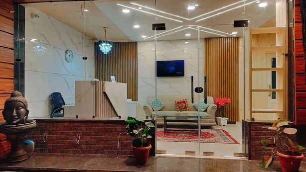 A modern living room with a sofa, a TV, a chandelier, and a Buddha statue. - kumar residency Mcleodganj (Dharamshala)