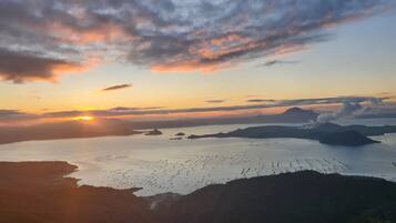 A coastal landscape with a sunset over a body of water and landforms.