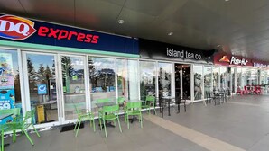 Zona comercial con una tienda DQ Express, una tienda Island Tea Co. y un restaurante Pizza Hut.