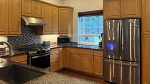 Une cuisine moderne avec des meubles en bois, des appareils électroménagers en acier inoxydable et une fenêtre donnant sur l’extérieur.
