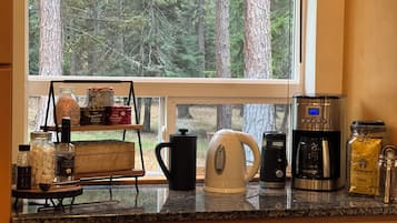 A kitchen counter with a coffee maker, kettle, and various condiments.