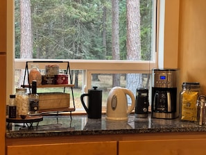 Una encimera de cocina con cafetera, hervidor y diferentes condimentos.