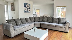 Ein modernes Wohnzimmer mit einem grauen Ecksofa, einem weißen Couchtisch und Holzboden.