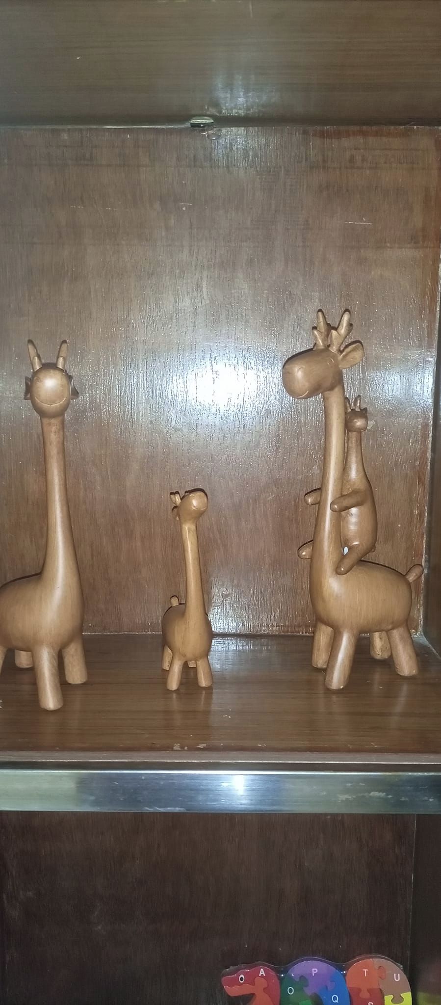 Un estante de madera con tres figuras de jirafa de madera.