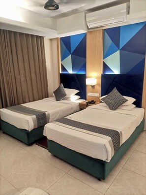 Ein Hotelzimmer mit zwei Betten, einem Nachttisch, einer Lampe und einem geometrischen Wanddesign.