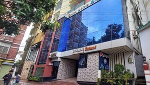 Un hôtel doté d’une façade moderne en verre, d’une enseigne Pepsi et d’un restaurant bien visible appelé BAR.B.O.