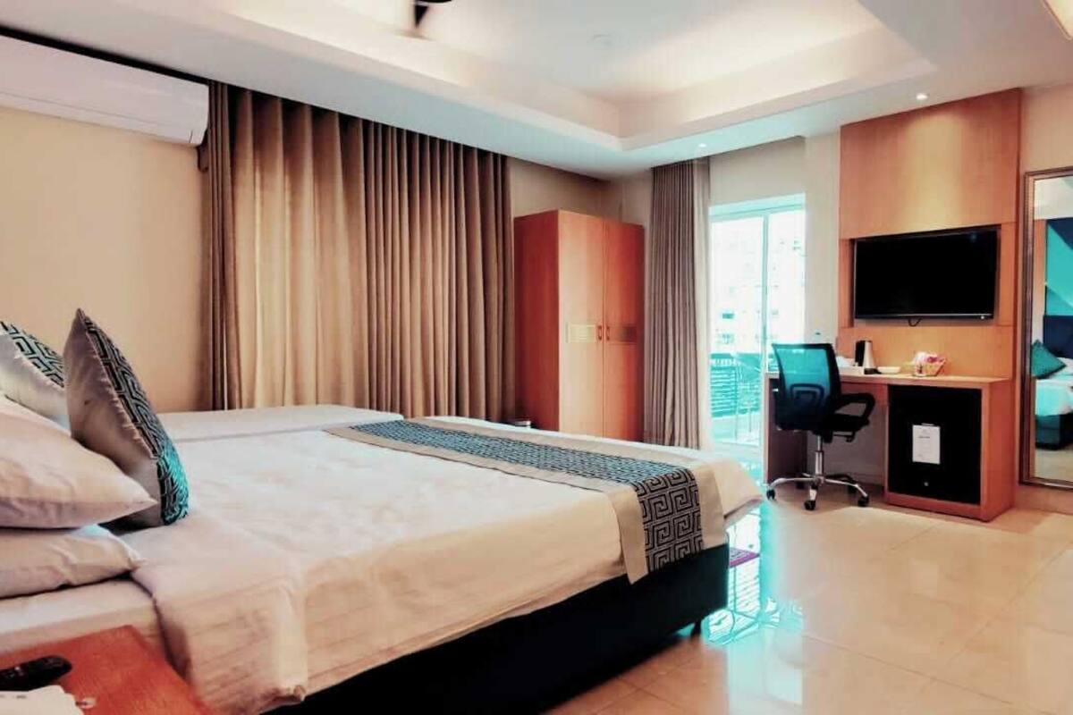 A hotel room with a bed, a desk, a TV, and a sliding door.