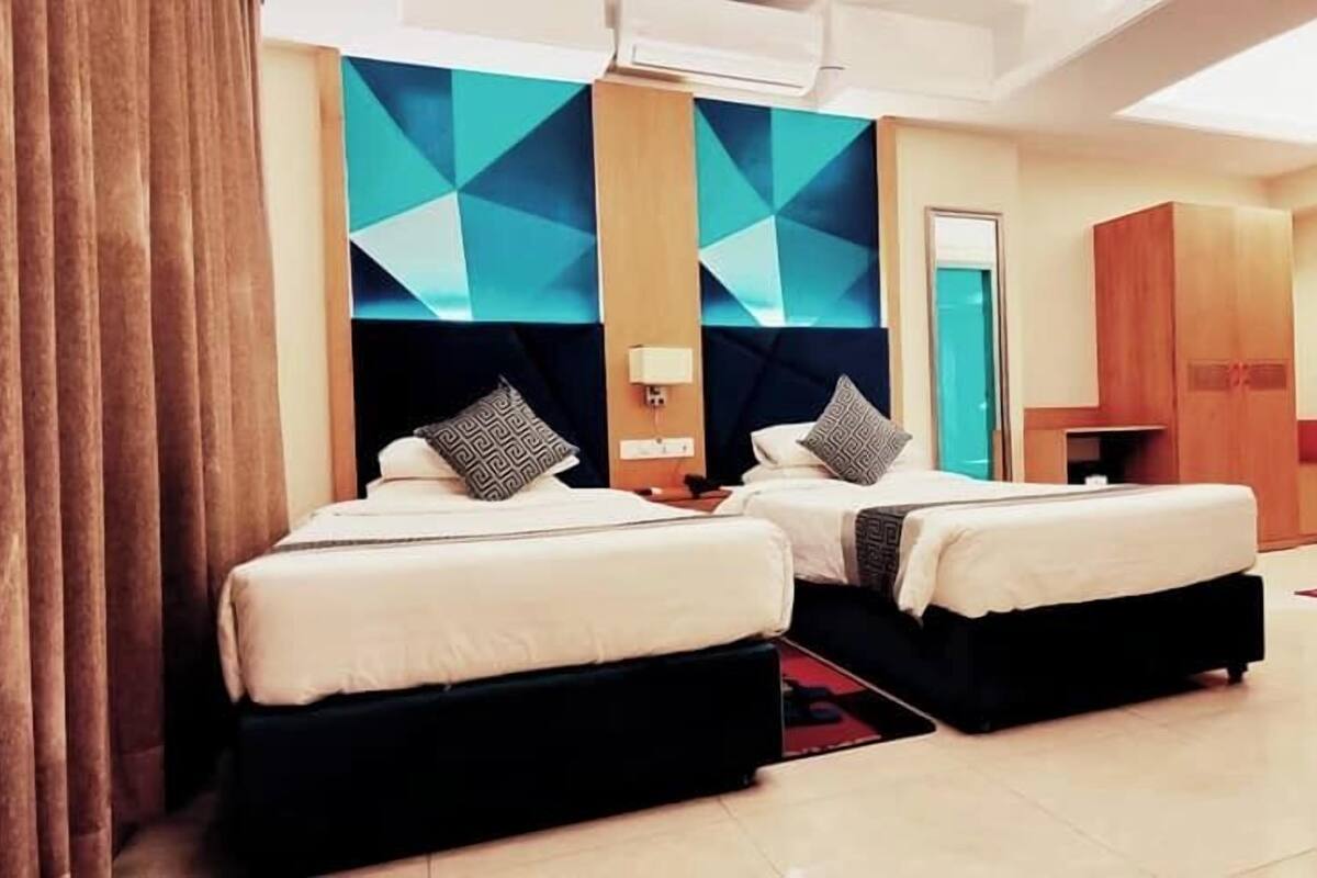 A hotel room with two beds, a geometric wall design, and a mirror.