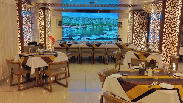 Un restaurant doté de nombreuses tables, chacune recouverte d’une nappe blanche et agrémentée de chaises disposées avec soin.
