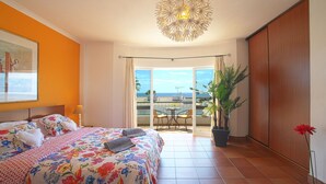 A bedroom with a bed, a potted plant, a balcony with a table and chairs, and a view of the sea. - Baia de Cristal by Interhome (Lagos)