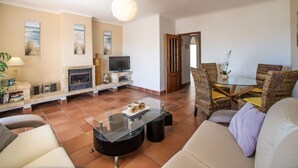 A living room with a fireplace, television, and wicker furniture. - Baia de Cristal by Interhome (Lagos)