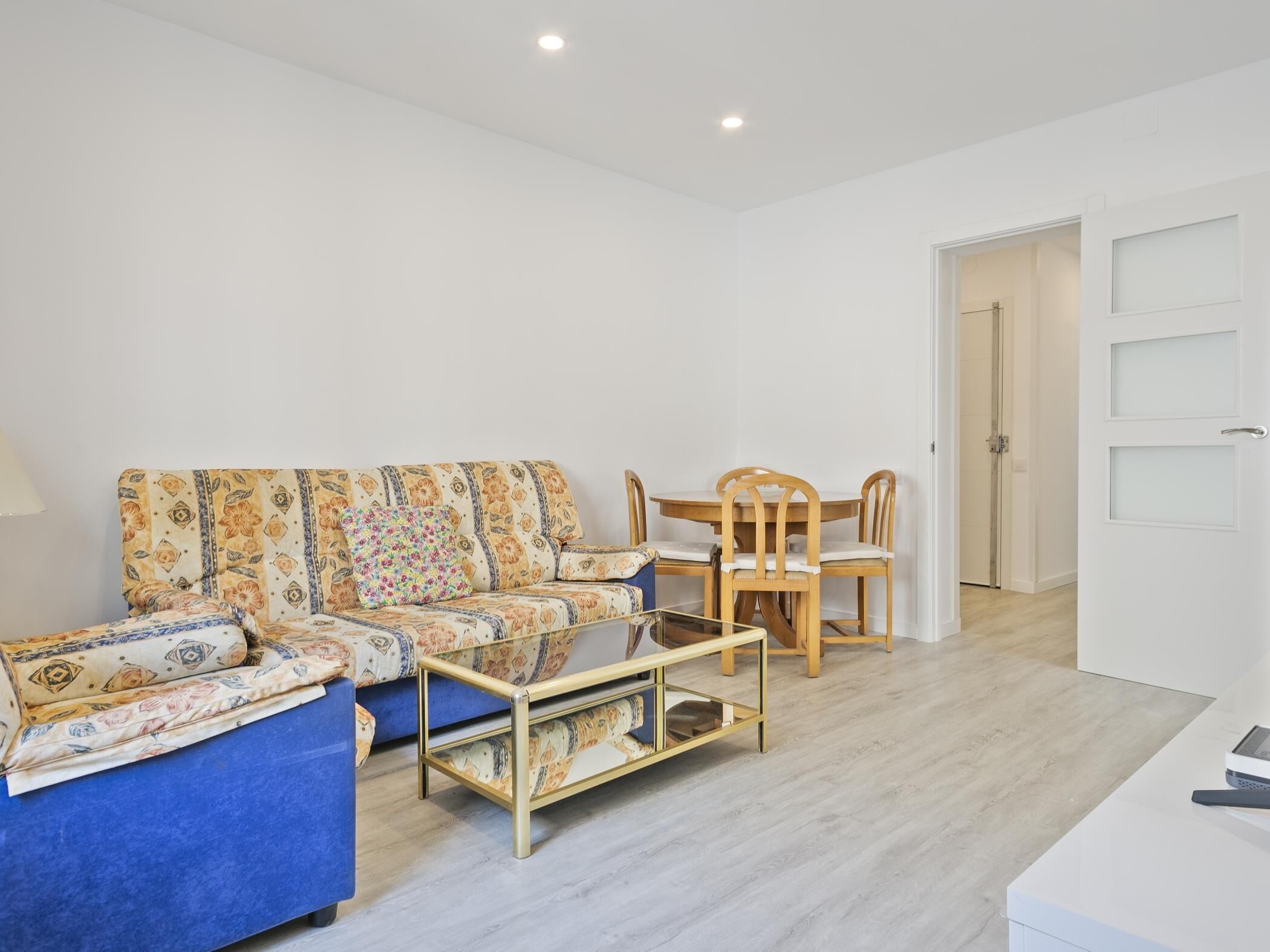 Una sala moderna con sofá, una mesa de centro y un comedor con sillas y una mesa.