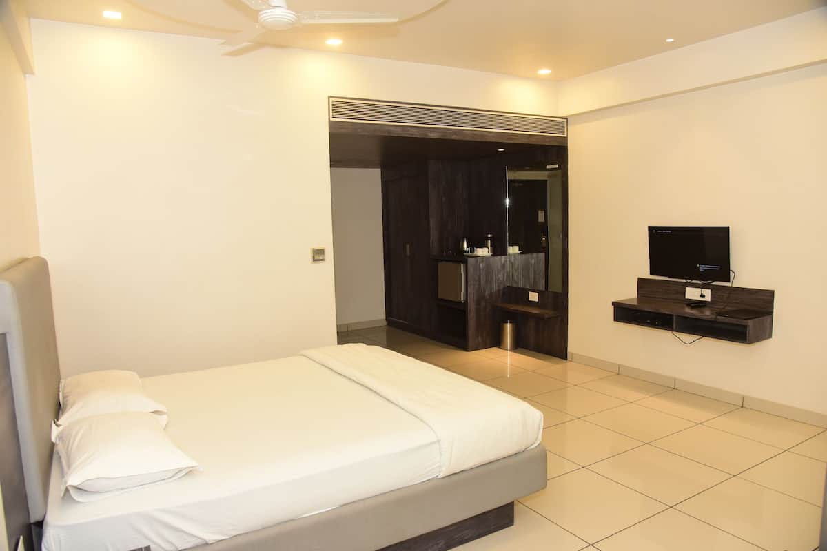 A modern bedroom with a bed, a TV mounted on the wall, and a bathroom visible through an open door.