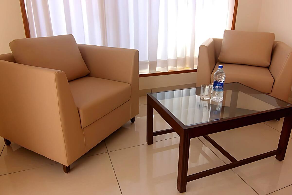 A modern living room with two beige sofas and a glass coffee table.