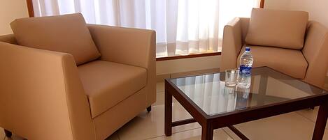 A modern living room with two beige sofas and a glass coffee table.