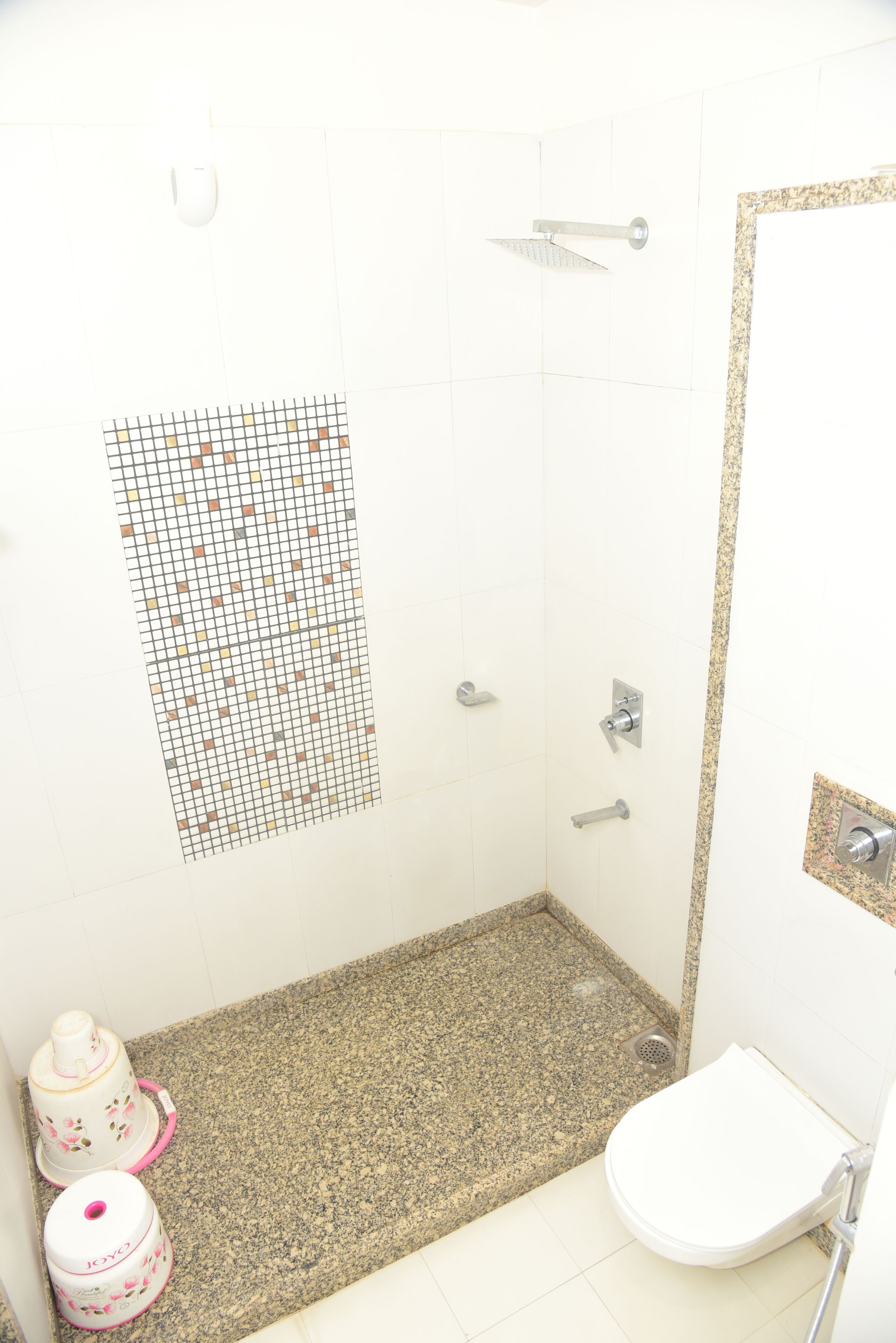 A bathroom with a shower, toilet, and two trash bins.