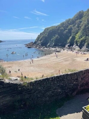 Une plage bordée de falaises rocheuses et aux eaux d’un bleu limpide.