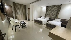 Una habitación de hotel moderna con una cama grande, un sofá, una mesita y un televisor.