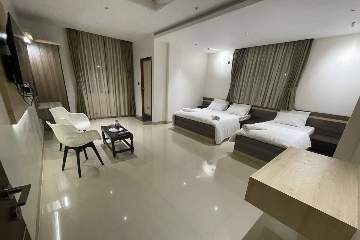 Une chambre d’hôtel moderne avec un grand lit, un canapé, une petite table et un téléviseur.