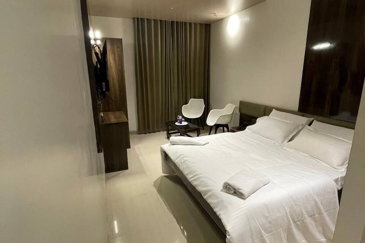 Une chambre d’hôtel moderne équipée d’un grand lit, d’un bureau, d’une chaise et d’un ventilateur de plafond.